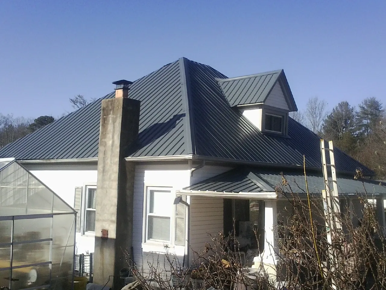Dark blue standing seam metal roof on a white farmhouse with dormer — Slate & Tile Roof Repair by Roofing Brothers in Ace