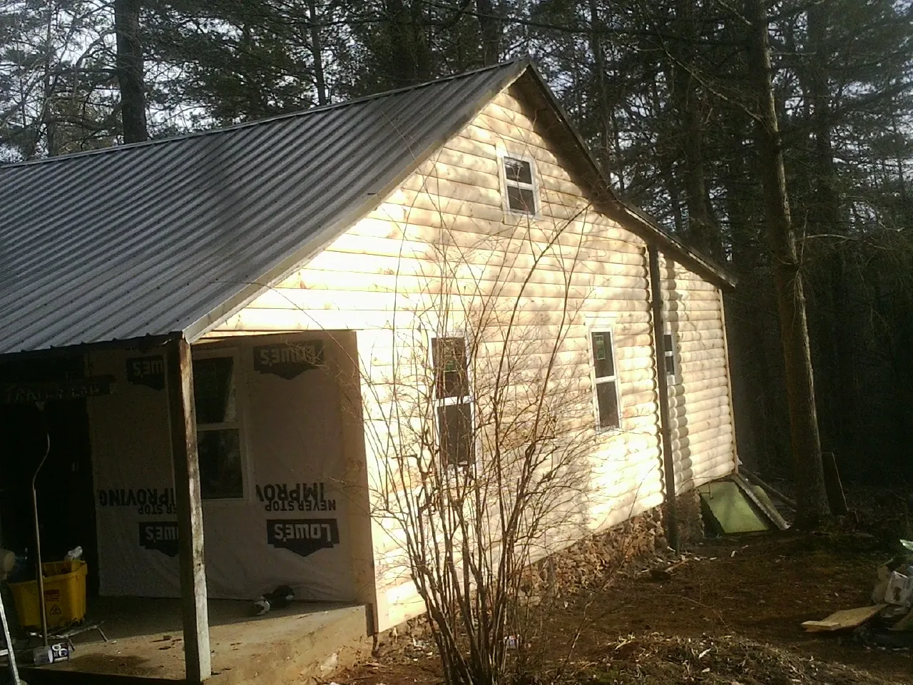 Log siding gable end under a dark metal roof edge in Ace