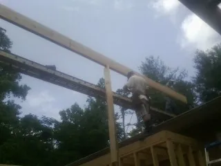 Carpenter setting a ridge beam over a new addition frame — Ice Dam Removal by Roofing Brothers in Ace