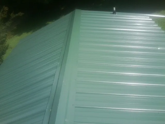 New green metal panels meeting at the ridge of a roof — Flat Roof Repair work by our crew in Ace