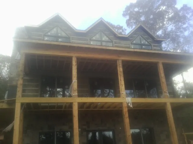 Dormers and porch framing on a large log home under construction — Roof Coating work by our crew in Ace