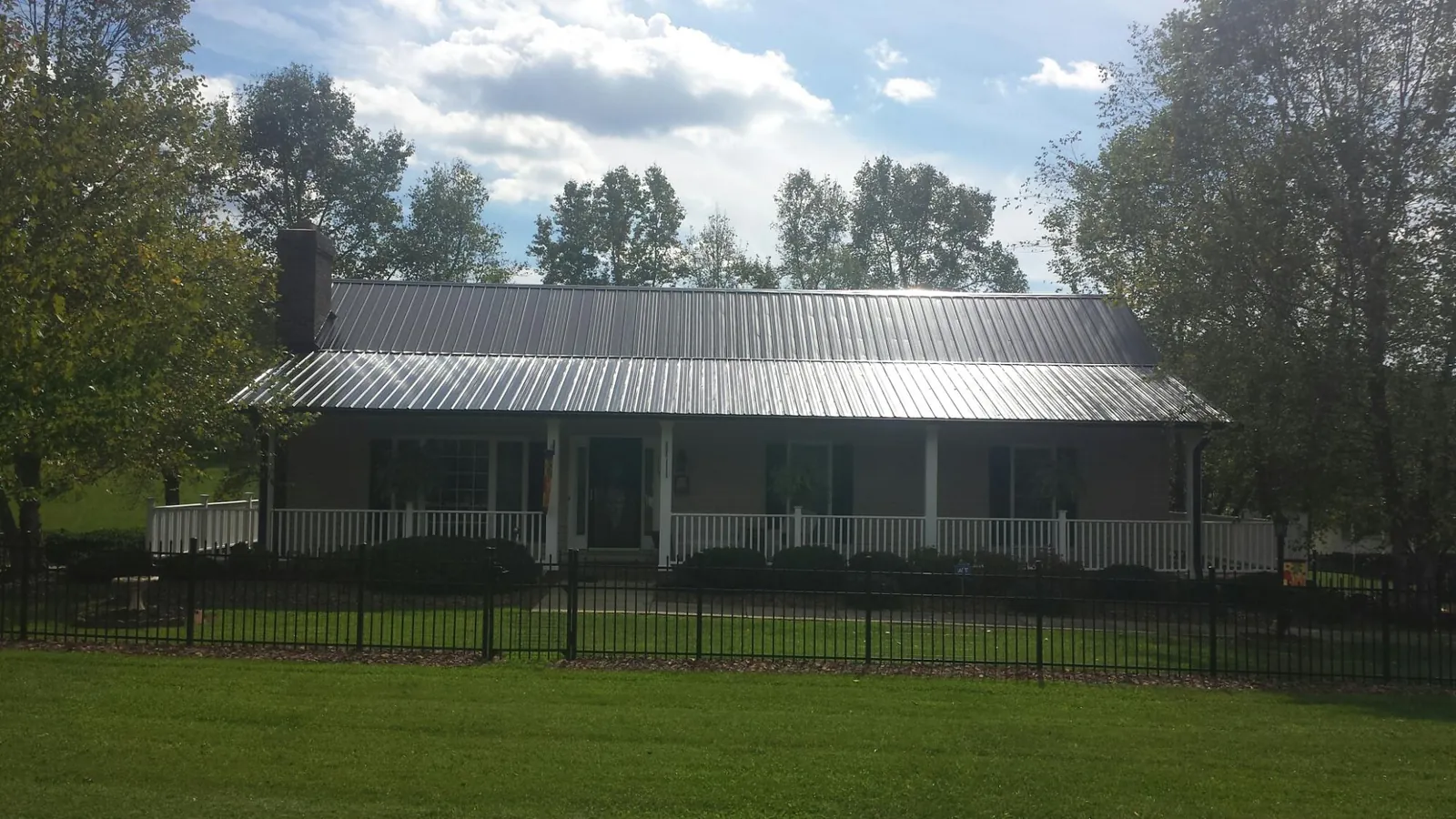 Gray metal roof on a brick ranch with a full width front porch — Gutter Guard Installation work by our crew in Ace